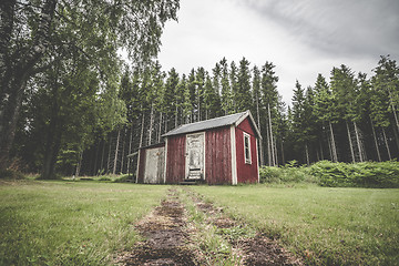 Image showing Red cabin in a swedish forest with pine trees