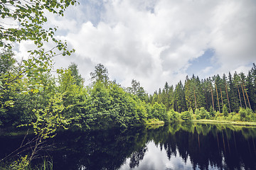 Image showing Dark lake in a forest with green trees reflecting