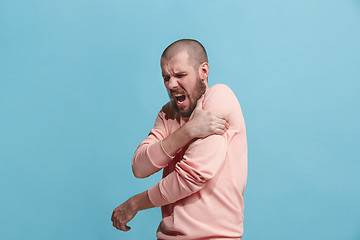 Image showing Young man overwhelmed with a pain in the shoulder .