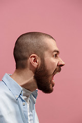 Image showing The young emotional angry man screaming on pink studio background