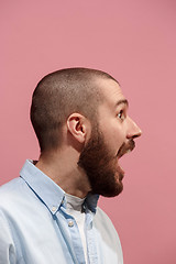 Image showing The young emotional surprising man screaming on pink studio background