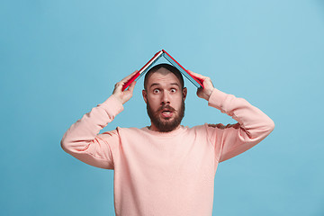 Image showing Businessman holding laptop on head at blue studio