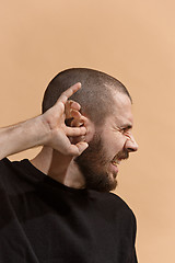 Image showing The Ear ache. The sad man with headache or pain on a pastel studio background.