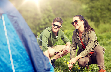 Image showing happy couple setting up tent outdoors