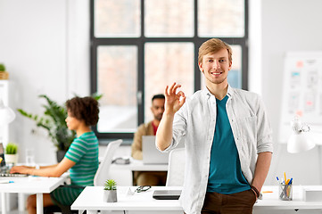 Image showing happy smiling man showing ok hand sign at office