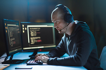 Image showing hacker with computer and headset in dark room