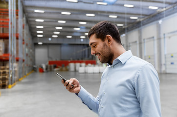 Image showing businessman with smartphone at warehouse