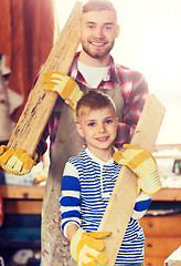 Image showing happy father and son with wood plank at workshop