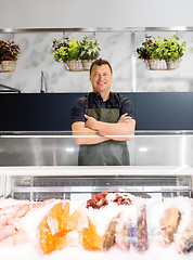 Image showing male seller with seafood at fish shop fridge