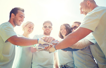 Image showing group of volunteers putting hands on top outdoors