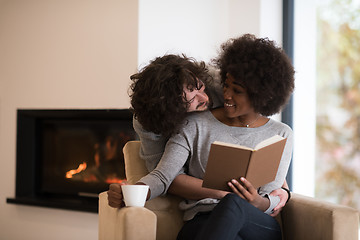 Image showing multiethnic couple hugging in front of fireplace