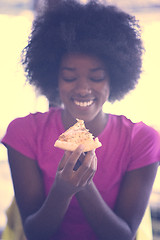 Image showing woman with afro hairstyle eating tasty pizza slice