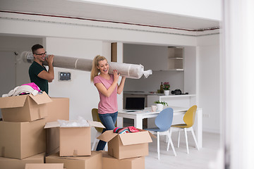 Image showing couple carrying a carpet moving in to new home