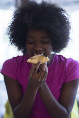 Image showing woman with afro hairstyle eating tasty pizza slice
