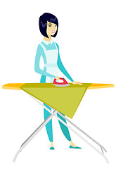 Image showing Asian maid ironing clothes on ironing board.