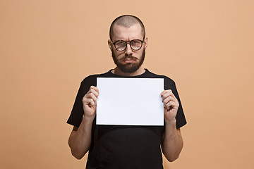 Image showing A young man holds an empty plate in his hands to fill your text. Emotional, courageous face.