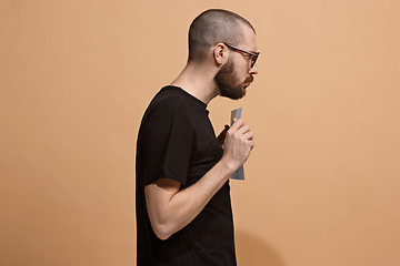 Image showing A young man holds an empty plate in his hands to fill your text. Emotional, courageous face.