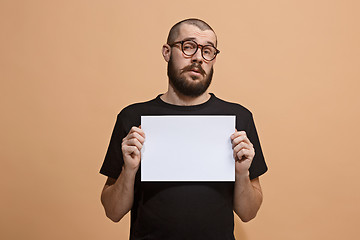 Image showing A young man holds an empty plate in his hands to fill your text. Emotional, courageous face.