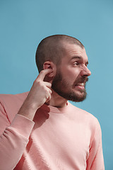 Image showing The Ear ache. The sad man with headache or pain on a blue studio background.