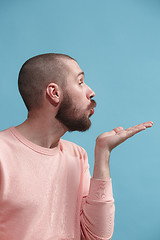 Image showing Isolated on blue young casual man kissing at studio