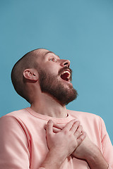 Image showing Isolated on blue young casual man smiling and enjoying at studio