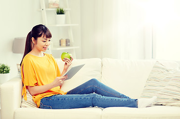 Image showing happy asian woman with tablet pc and apple at home