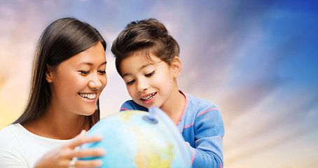 Image showing happy mother and daughter with globe over sky