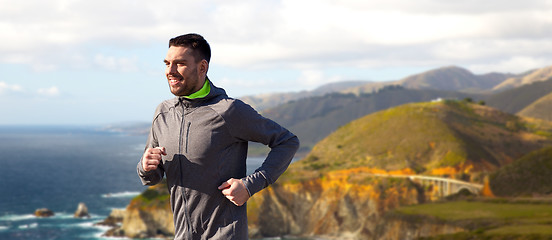 Image showing happy young man running over big sur coast