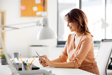 Image showing businesswoman with smartphone working at office