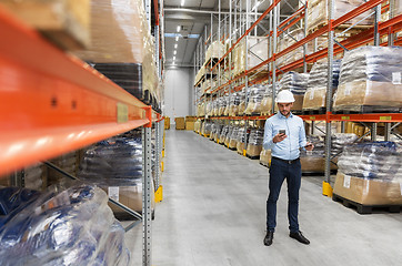 Image showing businessman in helmet with smartphone at warehouse