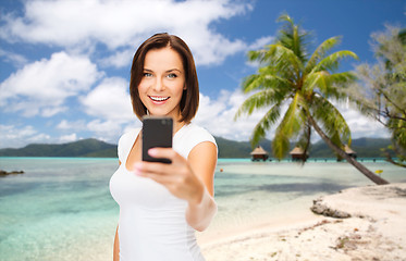 Image showing woman taking selfie by smartphone on beach