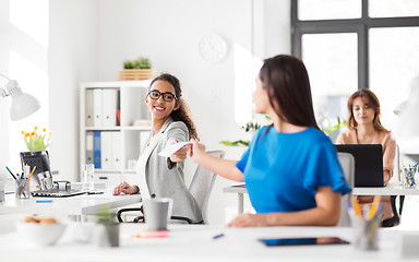 Image showing businesswomen giving each other papers at office