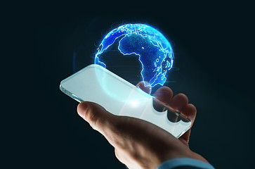 Image showing hand with smartphone and earth hologram