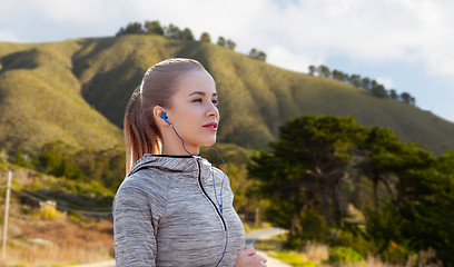 Image showing woman with earphones running over big sur hills