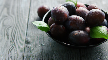 Image showing Wet purple plums in bowl