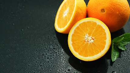 Image showing Orange with leaf on wet table 