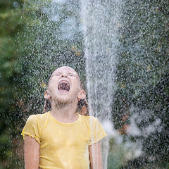 Image showing Happy little girl pouring water from a hose.