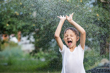 Image showing Happy little boy pouring water from a hose.