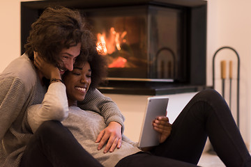 Image showing multiethnic couple using tablet computer on the floor