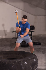 Image showing man workout with hammer and tractor tire