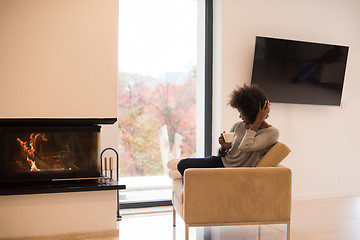 Image showing black woman drinking coffee in front of fireplace