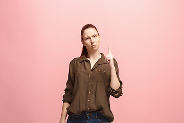 Image showing The serious business woman standing and looking at camera against pink background.