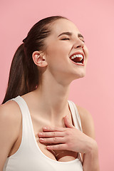 Image showing The happy woman standing and smiling against pink background.