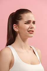 Image showing The young woman is looking sad on the pink background.