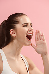 Image showing Isolated on pink young casual woman shouting at studio