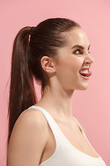 Image showing The young woman is looking crazy on the pink background.