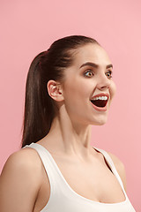 Image showing The happy woman standing and smiling against pink background.