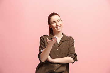 Image showing The happy business woman standing and smiling against pink background.