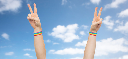 Image showing hands with gay pride rainbow wristbands make peace