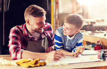 Image showing happy father and son with blueprint at workshop